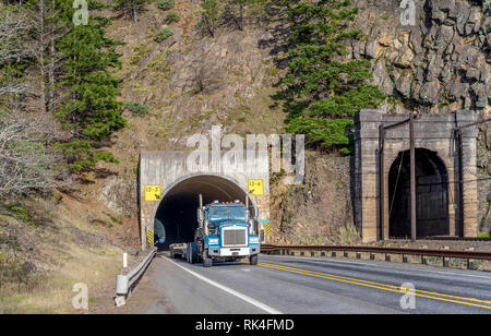 Gros camion bleu American long haul camion semi transport de fret commercial sur l'étape vers le bas semi-remorque qui traverse le tunnel sur la route étroite le long Banque D'Images