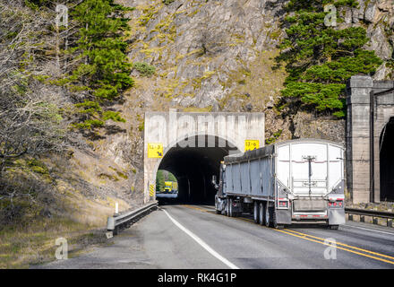 Deux gros camion camions semi long courrier commercial transport de fret dans les semi-remorques qui traversent le tunnel l'un vers l'autre sur la route étroite d'alon Banque D'Images