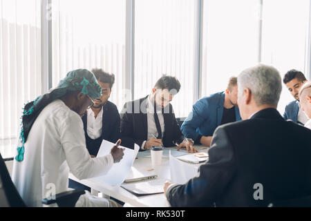 Investisseur arabe en blanc et gutra candura nationale sur la stratégie financière de l'entreprise tête de discuter avec son multirucial sexe masculin au cours d'une réunion Banque D'Images