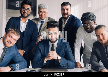 Les gens d'affaires multiculturelles dont l'arabe, du Caucase, Indienne, hispanique debout dans un bureau moderne dans le groupe et à la confiance à l'appareil photo. Conc Banque D'Images