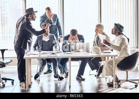 Mixed race de gens d'affaires de se quereller at desk in office. conversation émotionnelle parmi les partenaires étrangers Banque D'Images