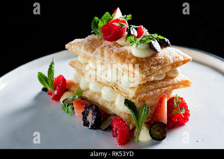 Mille-Feuilles moderne servi avec des baies sur une plaque ronde blanche Banque D'Images