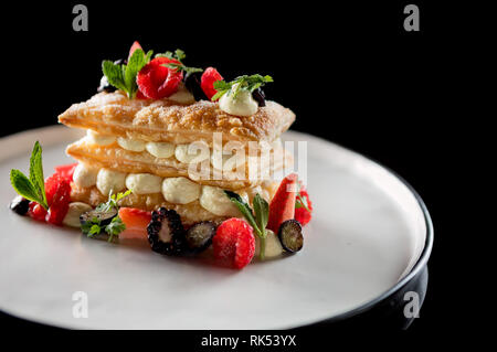 Mille-Feuilles moderne servi avec des baies sur une plaque ronde blanche Banque D'Images