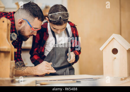 Carpenter la construction d'un nichoir en bois avec son enfant. Un petit fils participe activement au processus de la main. Professionnels de la paternité et DIY c Banque D'Images