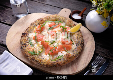 Pizza au saumon délicieux servi sur planche de bois Banque D'Images