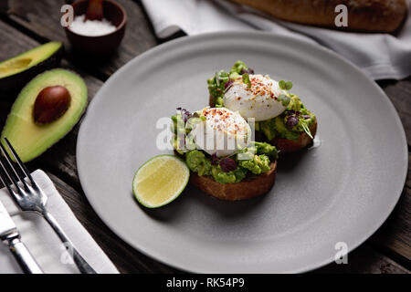 Deux œufs pochés sur toast à l'avocat d'épices sur une plaque ronde gris Banque D'Images