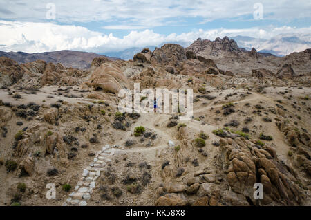 Randonneur femme promenades le long d'un sentier de terre à travers l'Alabama Hills à l'arche du départ du sentier en boucle Mobius Banque D'Images