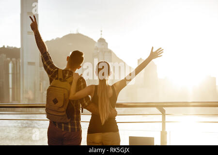 Couple heureux avec bras levés de soleil à souhaits grande ville. Hong Kong, Chine Banque D'Images