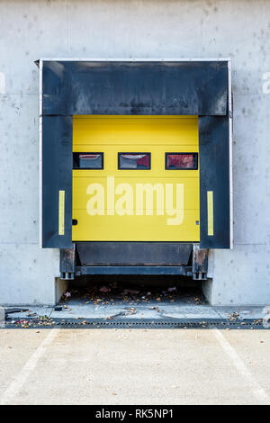 Vue de face d'une baie de chargement de camions avec des joints en caoutchouc dans le mur de béton d'un entrepôt dans la banlieue de Paris, France, avec un rouleau jaune s Banque D'Images