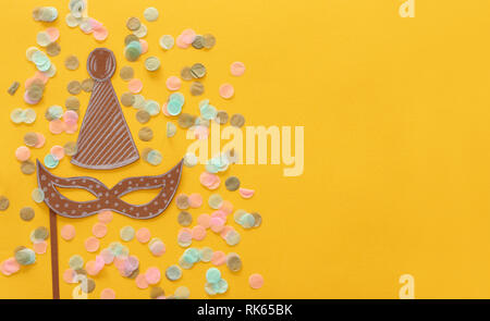 Carnival party celebration concept avec masque et clown papier chapeau sur fond jaune. Vue d'en haut. Mise à plat Banque D'Images