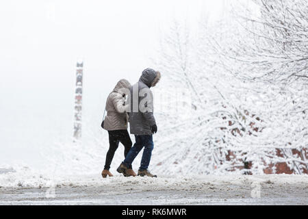 Washington, USA. 9 Feb 2019. Un couple traverse Virginia Street comme une forte tempête hivernale des couvertures Seattle en six pouces de neige. Dans la distance est un totem de cèdre de Victor Steinbrueck Park. Crédit : Paul Christian Gordon/Alamy Live News Banque D'Images