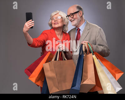 Couple heureux en tenant après selfies shopping avec de nombreux sacs Banque D'Images