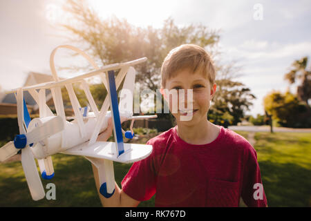 Happy Young boy avec un jouet avion en plein air à la recherche de l'appareil photo. Preteen boy playing with toy son avion.