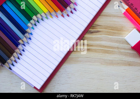 L'école et les fournitures de dessin, sur table en bois. Livre d'exercices, des crayons, une gomme et une règle. Avec l'exemplaire de l'espace. Banque D'Images