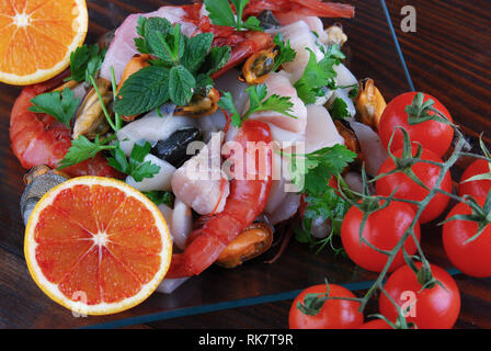 Plats en verre avec le poisson bonito mollusques et coquillages matières sur la planche de bois