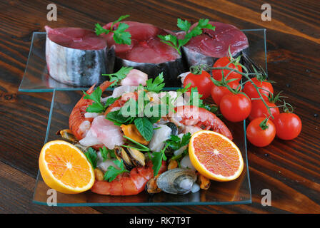 Plats en verre avec le poisson bonito mollusques et coquillages matières sur la planche de bois