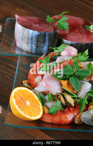 Plats en verre avec le poisson bonito mollusques et coquillages matières sur la planche de bois