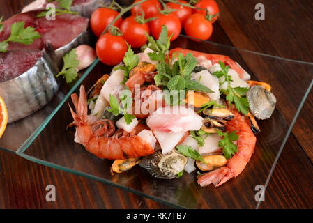 Plats en verre avec le poisson bonito mollusques et coquillages matières sur la planche de bois