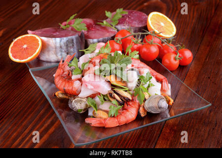 Plats en verre avec le poisson bonito mollusques et coquillages matières sur la planche de bois