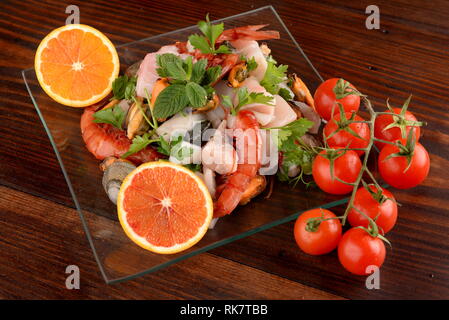 Plats en verre avec le poisson bonito mollusques et coquillages matières sur la planche de bois