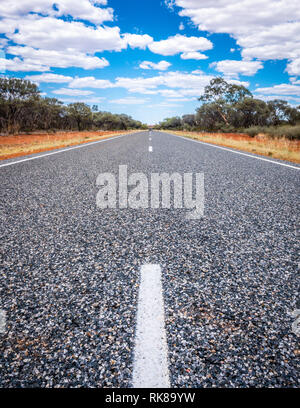 Route droite avec des lignes blanches au milieu du centre rouge de l'outback Australie NT Banque D'Images