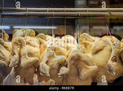 Ensemble avec les chefs des poulets pochés suspendu à un riz Poulet Hainanese hawker stall à Singapour Banque D'Images