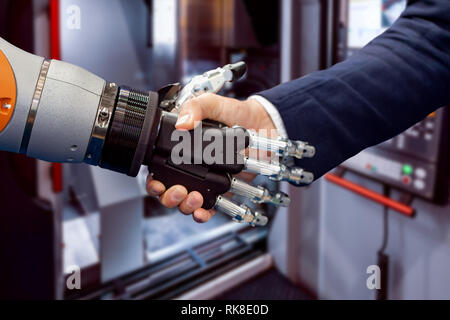 Main d'un businessman shaking hands with a robot Android. Le concept de l'interaction humaine avec l'intelligence artificielle. Banque D'Images