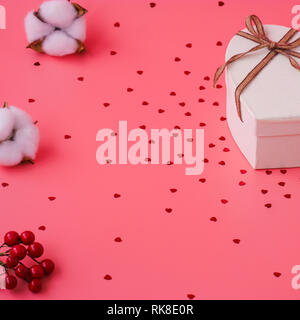Jour de la Saint-Valentin. Boîte-cadeau avec ruban or et rouges sur un fond rose. Maison de l'arrière-plan. Banque D'Images