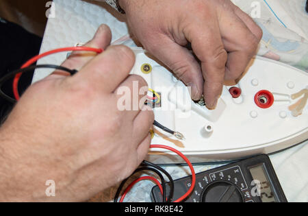 A proximité de l'ancien électricien, d'part, l'utilisation de voltmètre numérique d'une tension à réparer le fer à repasser électrique, selective focus Banque D'Images