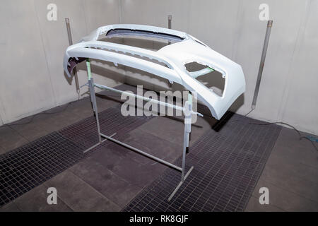 La réparation du pare-choc arrière d'une voiture blanche après un accident avec l'aide de multi-couleur mastic dans un atelier de peinture pour les véhicules dans une chamb Banque D'Images