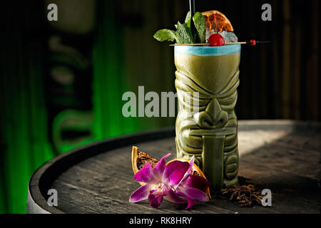 Boisson de Tiki fruitée et rafraîchissante servie dans une tasse de Tiki verte avec une menthe, une cerise et une orange sèche comme garniture Banque D'Images