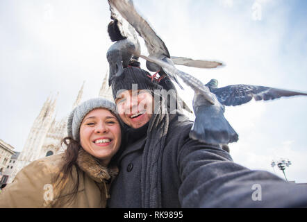 Les voyages, l'Italie et drôle - concept couple heureux touristes de prendre un autoportrait avec les pigeons en face de la Cathédrale de Duomo, Milan Banque D'Images