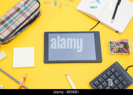 Les fournitures scolaires avec une tablette graphique sur fond jaune Banque D'Images