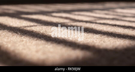 La lumière du soleil filtrant à travers les stores dans une fenêtre Créer une ombre et lumière sur une moquette beige. Droit avec une très faible profondeur de champ. Banque D'Images