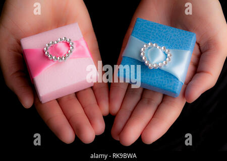 Mains tenant cadeau artisanal des boîtes bleues et roses Banque D'Images