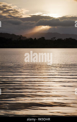 Coucher de soleil brillant à travers l'épaisse couverture nuageuse sur Tierra Oscura - vu de l'île de San Cristobal, l'archipel de Bocas del Toro, PANAMA Banque D'Images