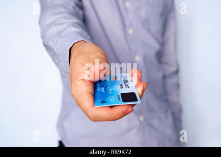 Casual young businessman à fond bleu de donner des cartes de crédit avec un scanner d'empreintes digitales sur sa face avant. Gros plan sur la prise mâle Banque D'Images