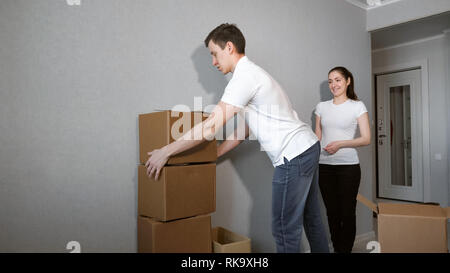 Couple Carrying Cases dans nouvelle maison le jour du déménagement Banque D'Images