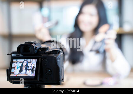 Asian woman blogger est montrant comment faire et l'utilisation des cosmétiques. En face de la caméra à l'enregistrement de vidéo en direct en streaming vidéo à la maison.des affaires en ligne Banque D'Images