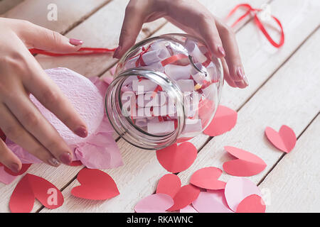 Lover's day. Pot en verre d'ouverture ou de date et désirs ou souhaits. Coeurs en papier rouge à l'arrière-plan. Banque D'Images