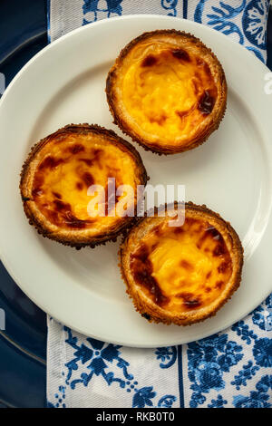 Pastel de Nata sur une plaque bleue avec des tuiles azulejo bleu et blanc Fond de serviette Banque D'Images