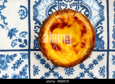 Un seul pastel de nata traditionnel sur l'Azulejo bleu et blanc Fond Serviette carreaux Banque D'Images