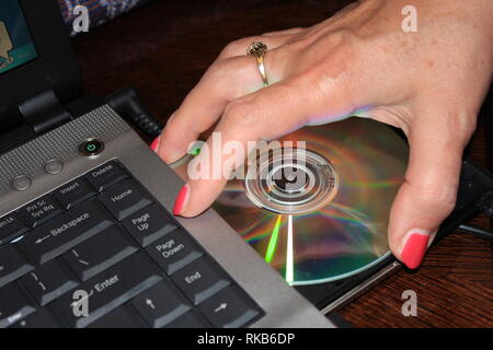 Insertion d'un CD par une main de womans Banque D'Images