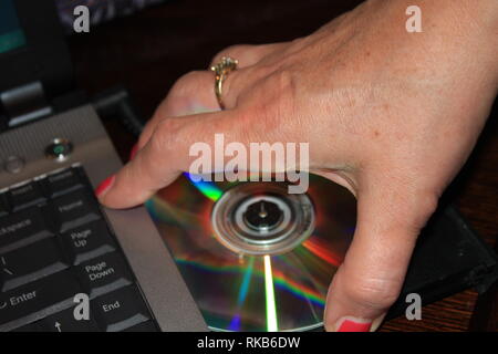 Insertion d'un CD par une main de womans Banque D'Images