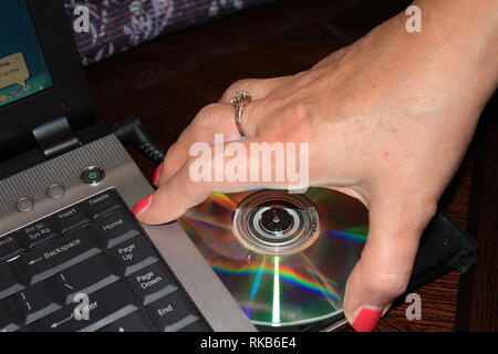 Insertion d'un CD par une main de womans Banque D'Images
