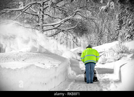 Un homme efface la neige des trottoirs à l'aide de la souffleuse à la campagne Banque D'Images