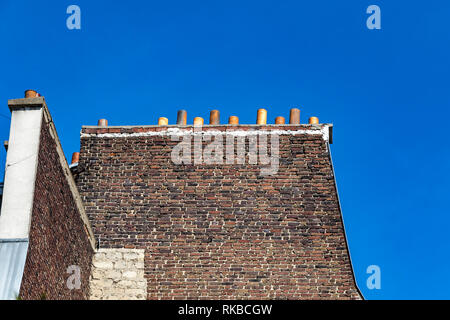 Des vieux mur de brique d'un côté d'un immeuble avec des cheminées contre un ciel bleu profond ,Paris , France Banque D'Images