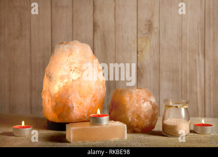 Sel de l'Himalaya, d'un savon sel de roche rose sous tension et lampe bougeoir de sel, avec une bougie brûlant à l'intérieur, avec des grains de sel sur la lumière bokeh background Banque D'Images