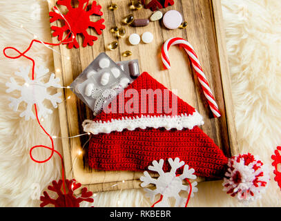 Vue de dessus de différentes pilules de vitamines comme cadeau de Noël dans la pantoufle de Jersey sur vintage plateau en bois avec impression flocons comme décoration. Idée cadeau conc Banque D'Images