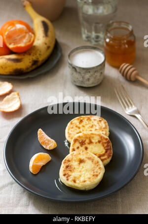 Petit déjeuner végétarien de quark des crêpes au miel, de fruits et de café avec du lait. Style rustique. Banque D'Images